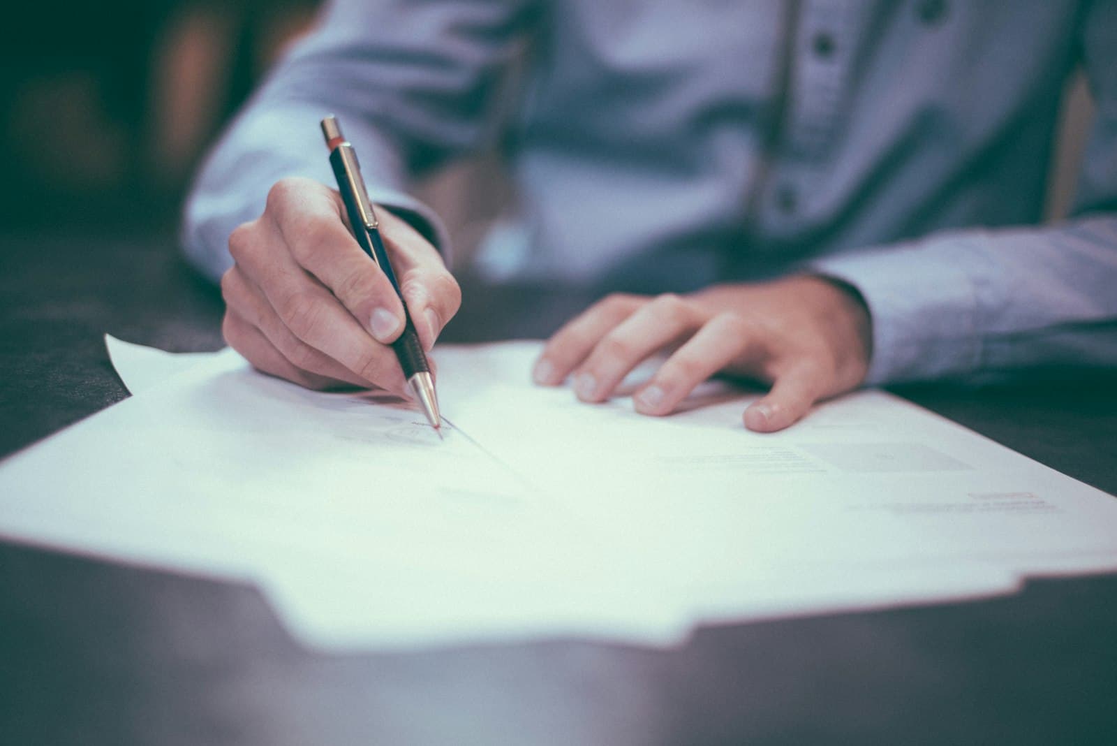 Persona firmando documentos en un escritorio de despacho