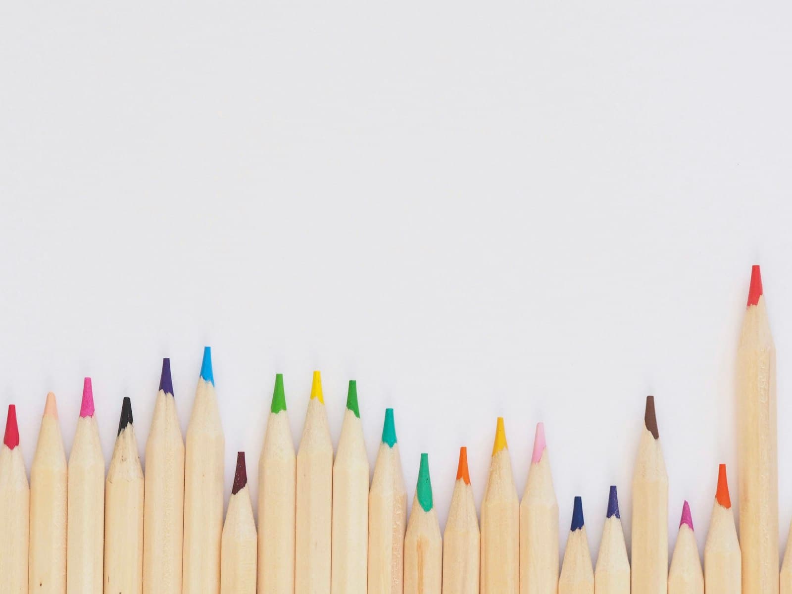 Lápices de colores alineados sobre una mesa blanca